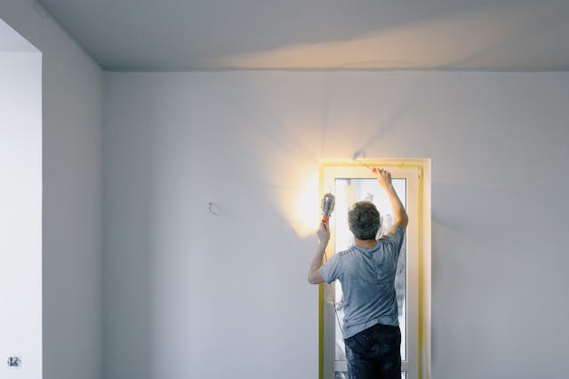 Person holding a flashlight pointed at an uninsulated window